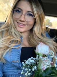 a woman wearing glasses and holding a bouquet of flowers in a car